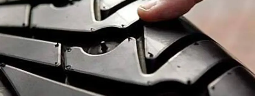 Imagen de un neumático y un dedo de un hombre apuntando a la ranura del dibujo