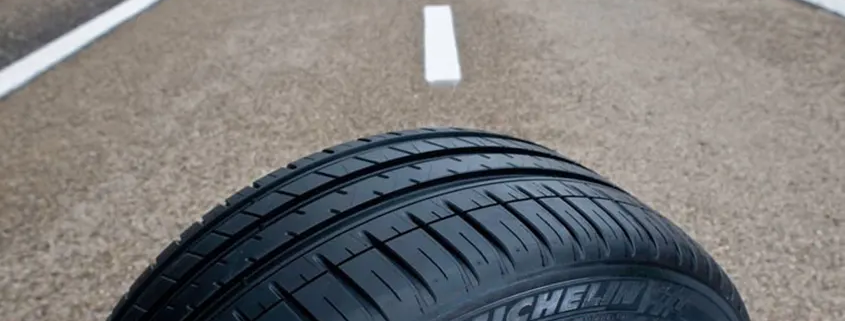 imagen de un neumático en una carretera que le hace de fondo a la foto, para ilustar que en Multirueda son especialistas en montaje de neumáticos
