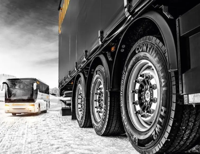 Imagen de un camióny un autobús circulando sobre una carretera nevada