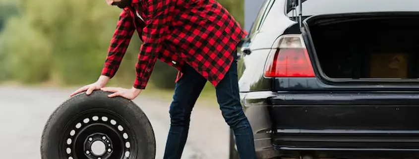 imagen dfe un hombre sacando una rueda de repuesto del maletero del coche
